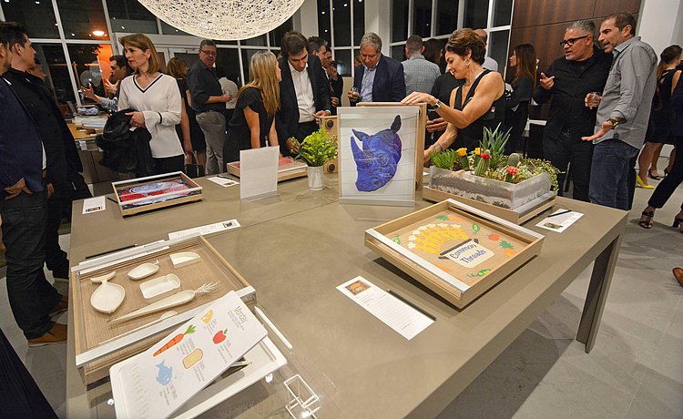 Overall view of guests mingling around the displayed art piece trays.