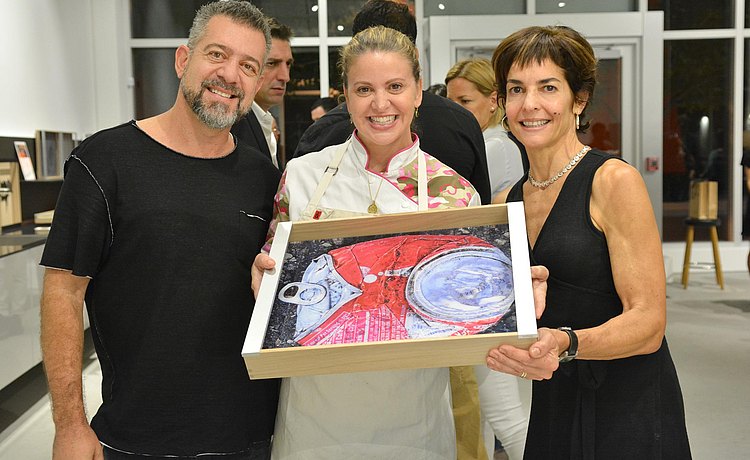 Chef Michelle Bernstein holding one of the art piece trays with guests.